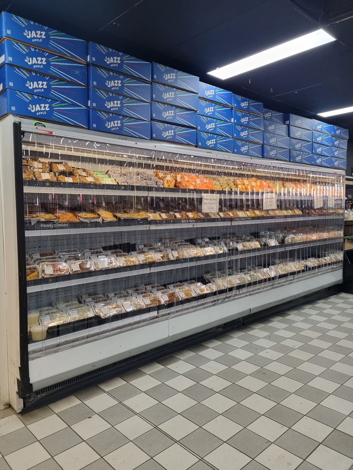 Night covers pulled down over a run of chilled display cabinets in a grocery aisle