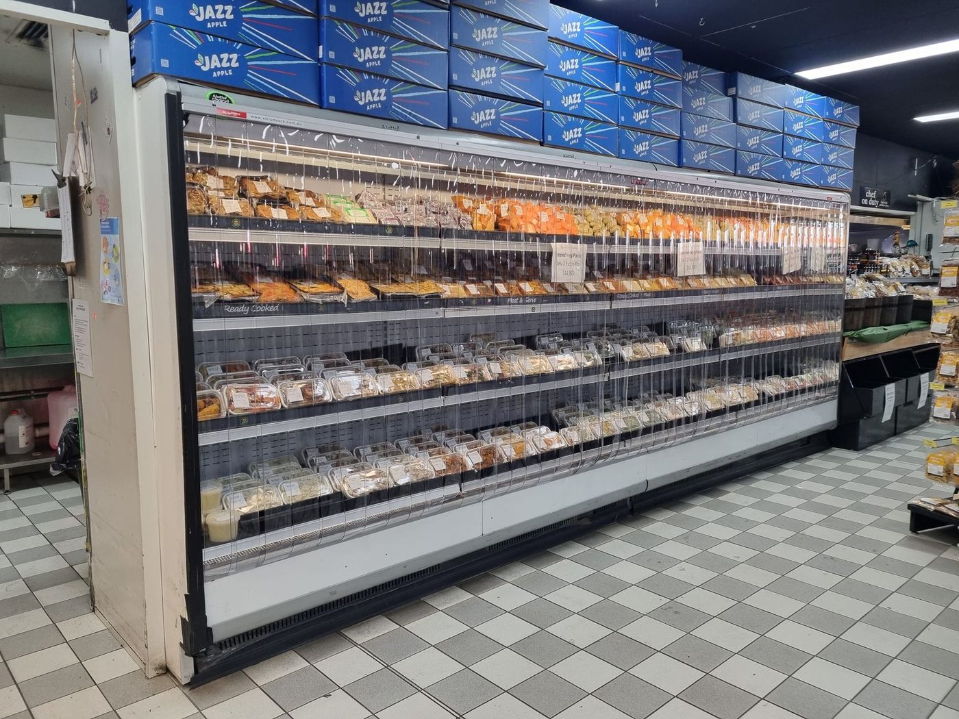 Night covers fitted to a long run of refrigerated deli and dairy cabinets