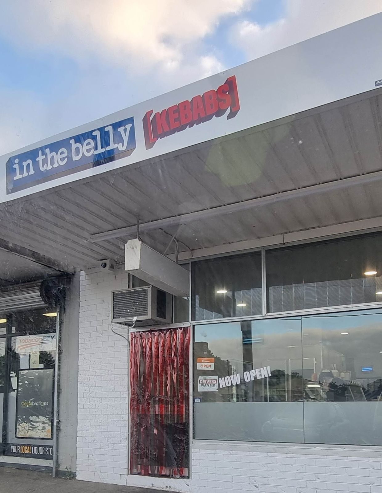 Red PVC strip curtain on the front door of In The Belly Kebabs