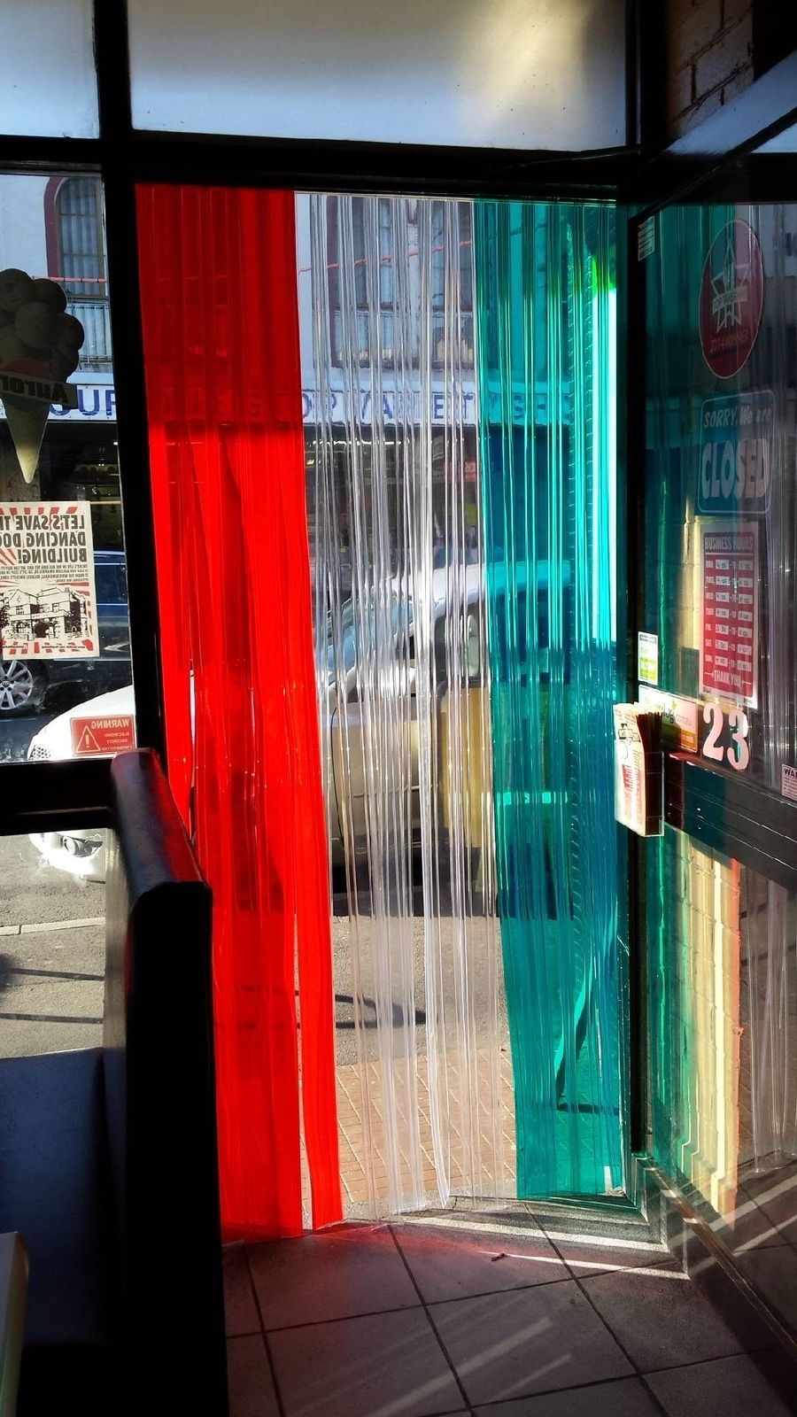Green, white and red PVC strip curtain seen from inside a food shop looking out to the street