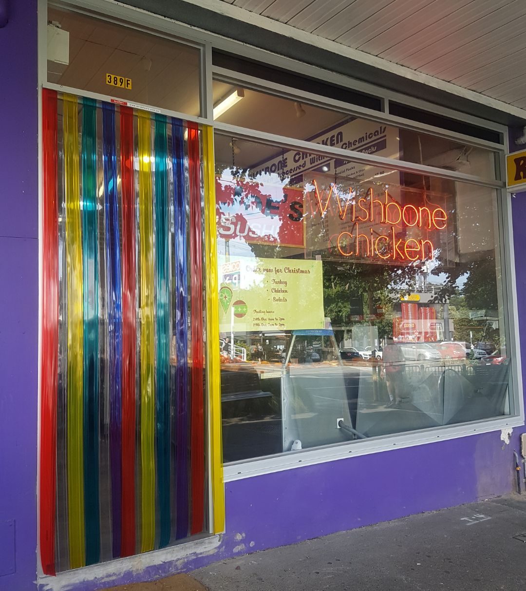 Multicoloured PVC strip curtain on the front door of a chicken shop with a purple shopfront