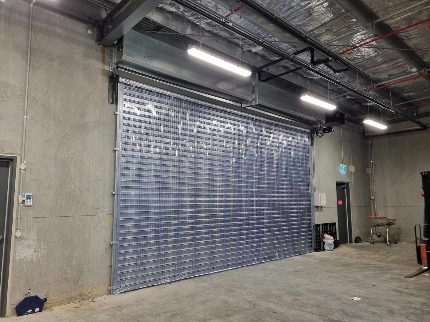 Clear PVC strip curtain across a wide industrial workshop opening